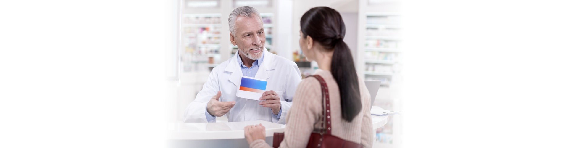 Best choice. Mature handsome male pharmacist holding drug while chatting with client